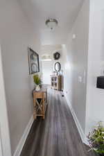 Hall with dark wood-type flooring, arched walkways, and baseboards