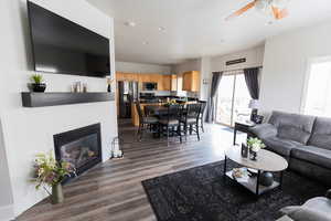 Living area with ceiling fan, recessed lighting, a glass covered fireplace, and wood finished floors