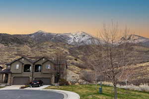 View of front of home with stucco siding, a lawn, an attached garage, a mountain view, and concrete driveway
