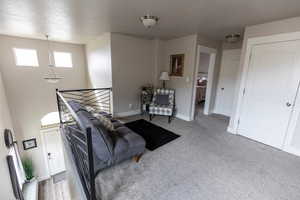 Sitting room with carpet flooring, an upstairs landing, and baseboards