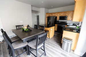 Kitchen with a kitchen island, appliances with stainless steel finishes, a sink, dark countertops, and light wood finished floors
