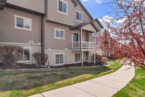Back of house with stucco siding and a yard