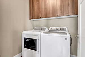 Laundry room with baseboards, cabinet space, and washer and clothes dryer