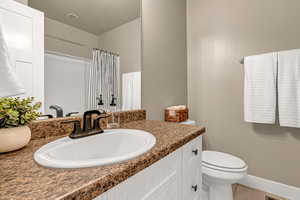 Bathroom featuring baseboards, toilet, tile patterned floors, vanity, and a shower with curtain