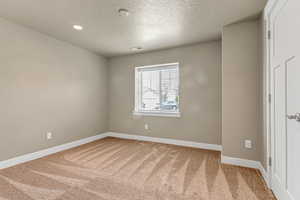 Unfurnished bedroom with recessed lighting, carpet flooring, baseboards, and a textured ceiling