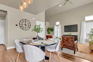 Dining room with baseboards, wood finished floors, a towering ceiling, and a ceiling fan