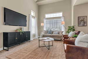 Living room featuring baseboards, carpet flooring, and a high ceiling