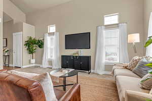 Carpeted living room featuring baseboards and a towering ceiling
