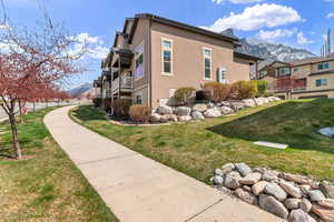 View of side of property featuring a mountain view, stucco siding, and a yard