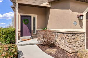 View of exterior entry featuring stucco siding and stone siding
