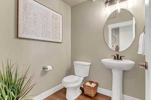 Bathroom with toilet, baseboards, and wood finished floors