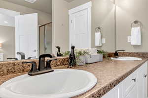 Bathroom featuring double vanity, a sink, and a stall shower