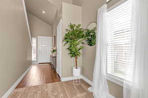 Foyer with baseboards, lofted ceiling, and wood finished floors