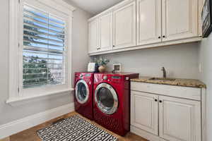 Laundry room with a sink, loads of cabinet space and included washer and dryer set.