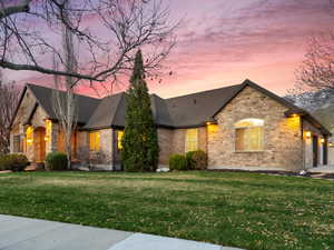 French country style house with stone siding, fence, a shingled roof, a garage, and a yard
