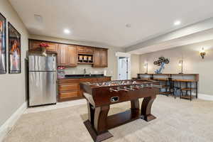 Living room featuring kitchenette/bar area, light colored carpet and recessed lighting