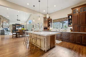 Kitchen with a fireplace, a sink, open shelves, and wood finished floors