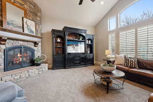 Living room featuring a ceiling fan, a stone fireplace, high vaulted ceiling, and huge windows with mountain views.