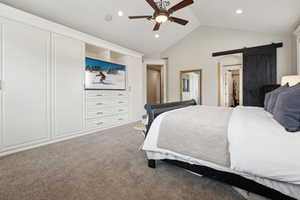 Carpeted bedroom with a ceiling fan, a barn door, vaulted ceiling, and recessed lighting