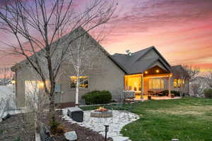 Rear view of house with a fire pit, stucco siding, a patio area, and a lawn