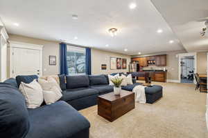Living room featuring light colored carpet, recessed lighting and a separate entry as well as a kitchenette/bar area.