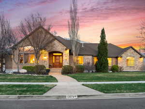 French country inspired facade with stone siding, brick siding, and a front yard
