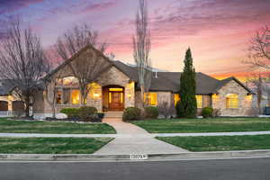 French country inspired facade featuring stone siding, brick siding, a yard, and roof with shingles