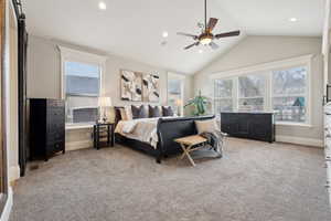 Bedroom with light carpet, baseboards, multiple windows, and vaulted ceiling