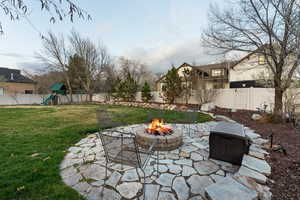 View of patio with an outdoor fire pit, a fenced backyard, mountain views and a playset.