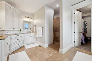 Primary Ensuite Bathroom featuring vanity, a spacious closet, baseboards, walk in shower, and visible vents