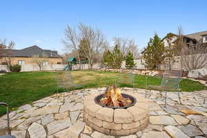 View of patio with a fenced backyard, a fire pit, mountain views and a playset.