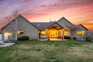 Back of property with a lawn, stucco siding, a patio area, and a hot tub