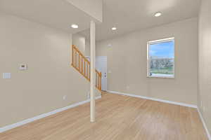 Spare room featuring baseboards, light wood-type flooring, recessed lighting, and stairs
