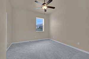 Spare room featuring ceiling fan, light colored carpet, and baseboards