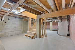 Unfinished below grade area featuring heating unit and stairs