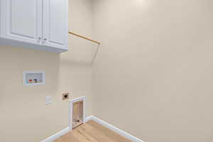 Washroom featuring hookup for an electric dryer, baseboards, light wood-style floors, hookup for a washing machine, and cabinet space