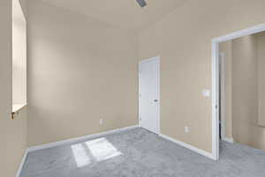 Carpeted spare room with baseboards and a ceiling fan