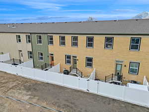 Multi unit property featuring board and batten siding, a shingled roof, a fenced backyard, and brick siding