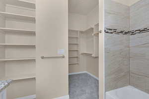 Bathroom with a walk in closet, shower / bath combination, and baseboards
