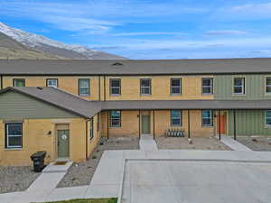 Multi unit property featuring brick siding, roof with shingles, and a mountain view