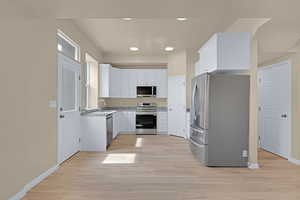 Kitchen with white cabinetry, light wood-type flooring, and appliances with stainless steel finishes