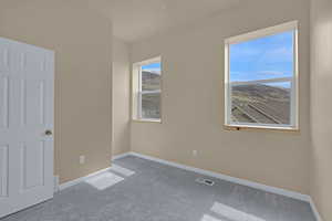 Carpeted empty room with visible vents and baseboards