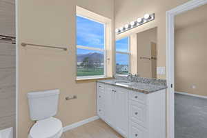 Bathroom with toilet, vanity, baseboards, and a mountain view