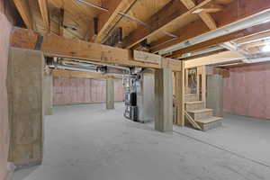 Unfinished below grade area featuring heating unit and stairway