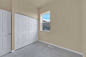 Unfurnished bedroom featuring a closet, carpet, visible vents, and baseboards