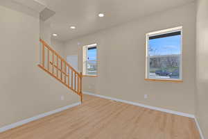 Empty room featuring baseboards, wood finished floors, and a healthy amount of sunlight