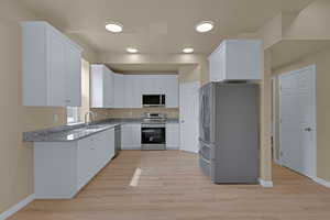Kitchen with a sink, white cabinetry, light stone counters, and stainless steel appliances