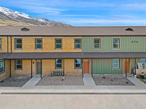 Townhome / multi-family property with brick siding, board and batten siding, a mountain view, and a shingled roof