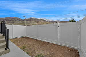View of yard featuring a fenced backyard, a mountain view, and a gate