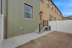 View of exterior entry with board and batten siding and fence
